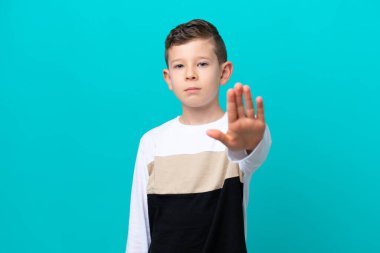 Küçük çocuk mavi arka planda izole edilmiş bir şekilde duruyor.