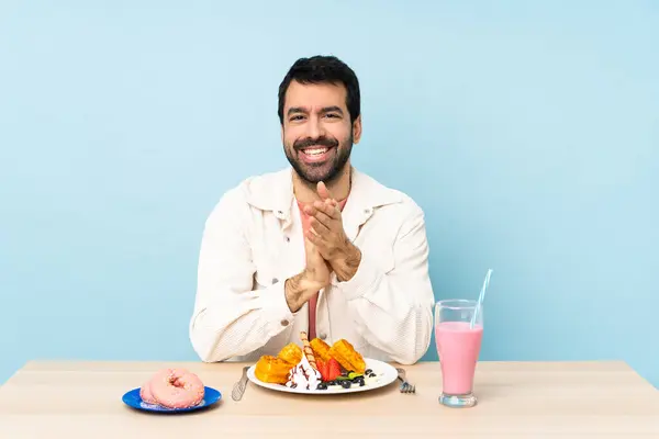 Man Vid Ett Bord Med Frukost Våfflor Och Milkshake Applåderar — Stockfoto