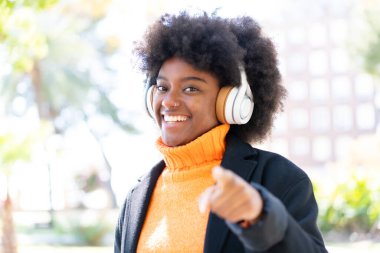 Afro-Amerikalı kız açık havada müzik dinliyor.