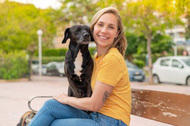 Dışarıda sevimli siyah köpeği olan genç sarışın kadın.