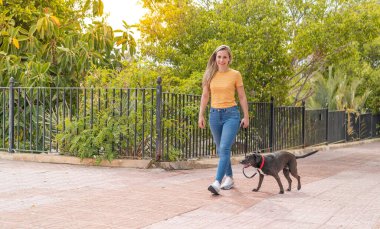 Dışarıda sevimli siyah köpeği olan genç sarışın kadın.