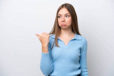 Genç Litvanyalı kadın beyaz arka planda izole edilmiş mutsuz ve kenarı işaret ediyor.