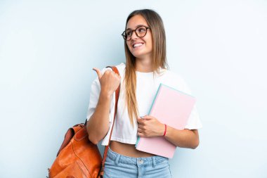 Mavi arka planda izole edilmiş genç bayan bir ürünü sunmak için kenarı işaret ediyor.