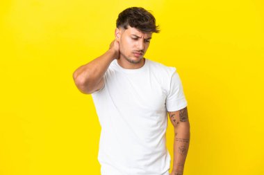Sarı arka planda boynu ağrıyan, beyaz, yakışıklı genç bir adam.