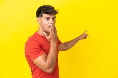 Sarı arka planda yalıtılmış beyaz, yakışıklı genç bir adam. Sürpriz bir ifadeyle.