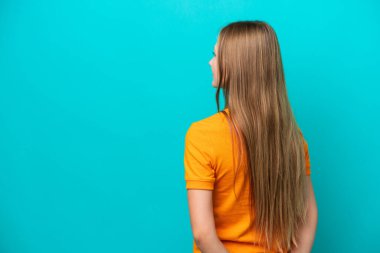 Genç Rus kadın mavi arka planda izole edilmiş ve arkasına bakıyor.