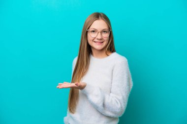 Mavi arka planda izole edilmiş genç bir Rus kadın gülümserken bir fikir sunuyor.