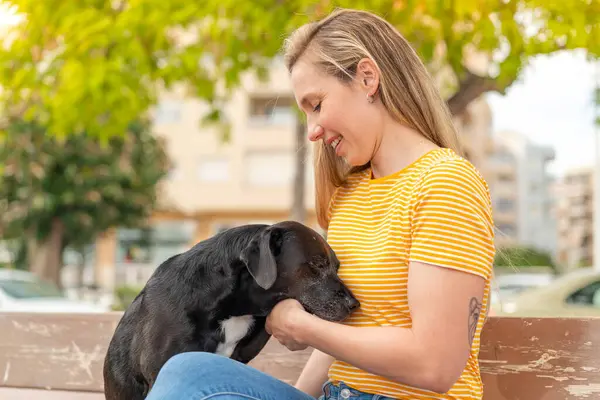 Dışarıda sevimli siyah köpeği olan genç sarışın kadın.