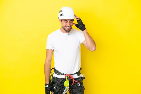 Young rock- climber man isolated on yellow background laughing