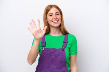 Beyaz arka planda izole edilmiş genç kızıl saçlı kadın parmaklarıyla beşi sayıyor.