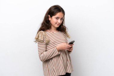 Beyaz arka planda izole edilmiş küçük bir kız cep telefonuyla mesaj gönderiyor.