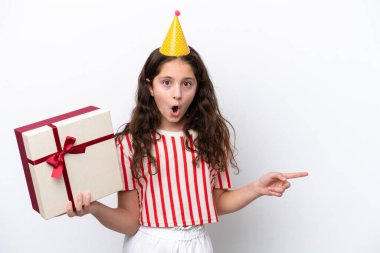 Küçük beyaz kız doğum günü hediyesini kutluyor. Beyaz arka planda, sürpriz bir yüz ifadesiyle izole edilmiş.