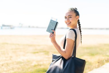 Dışarıdaki Faslı genç kız elinde mutlu bir ifadeyle bir pasaport tutuyor.