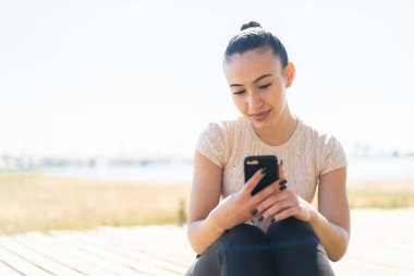 Dışarıdaki Faslı genç kız cep telefonu kullanıyor.