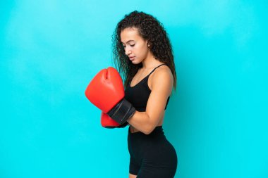 Genç Arap kadın mavi arka planda boks eldivenleriyle izole edilmiş.