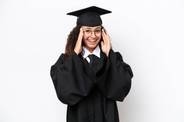 Üniversite mezunu genç bir Arap kadın beyaz arka planda gözlüklü ve şaşırmış.