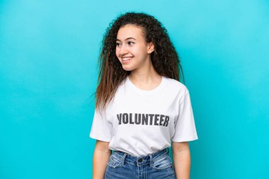 Mavi arka planda izole edilmiş genç bir Arap gönüllü kadın.