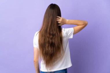 Kafkasyalı genç bir kadın mavi arka planda izole edilmiş ve düşünüyor.