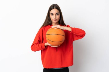 Beyaz arka planda basketbol oynayan beyaz tenli genç kadın.