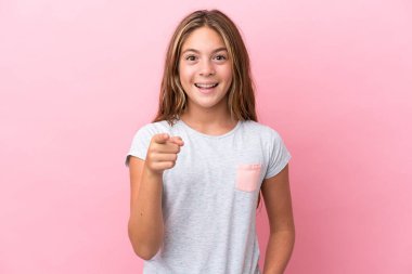 Pembe arka planda izole edilmiş küçük beyaz kız şaşırmış ve ön tarafı işaret ediyor.