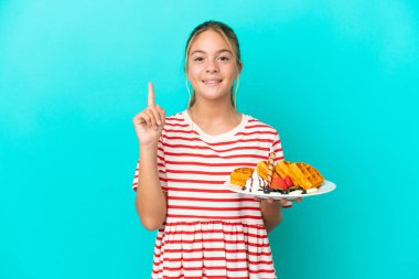 Mavi arka planda gözleme tutan küçük beyaz kız harika bir fikre işaret ediyor.