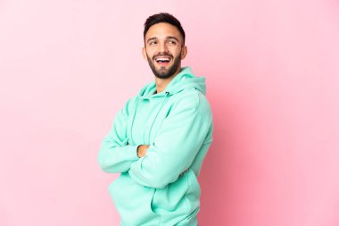 Pembe arka planda izole edilmiş genç beyaz adam mutlu ve gülümsüyor.