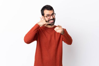 Beyaz arka planda sakallı, beyaz saçlı, beyaz saçlı, telefon hareketleriyle ön tarafı işaret eden beyaz bir adam.