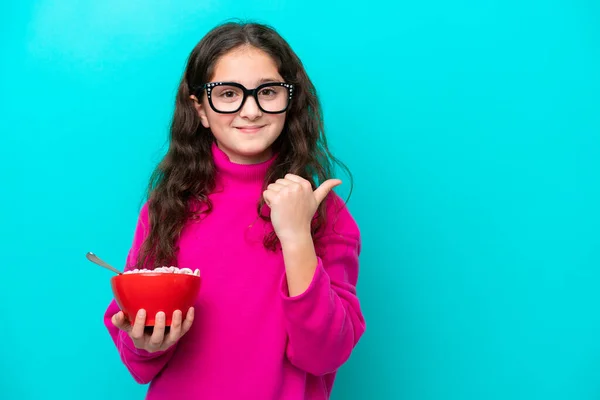 Little Girl Holding Bowl Cereals Isolated Blue Background Pointing Side — Stock Photo, Image