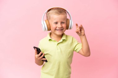 Küçük Rus çocuk pembe arka planda izole edilmiş müzik dinliyor.