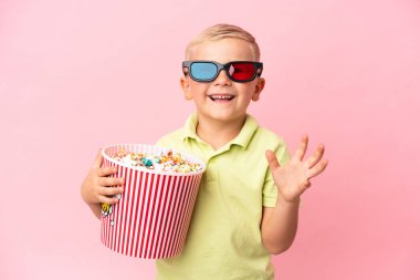 Küçük Rus çocuk izole bir arka planda büyük bir kasede patlamış mısır yiyor.