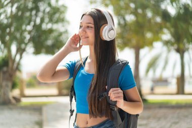 Genç kız açık havada müzik dinliyor.