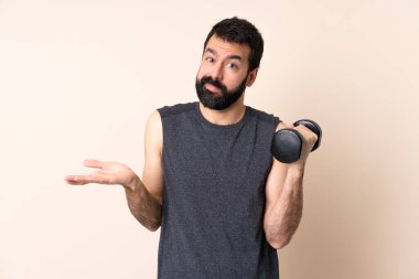 Beyaz sakallı sporcu izole edilmiş arka planda ağırlık kaldırıyor.