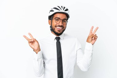 Beyaz arka planda izole edilmiş bisiklet kaskı tutan genç iş adamı iki eliyle zafer işareti gösteriyor.