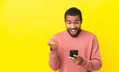 Sarı arka planda izole edilmiş genç Latin adam şaşırdı ve bir mesaj gönderiyor.