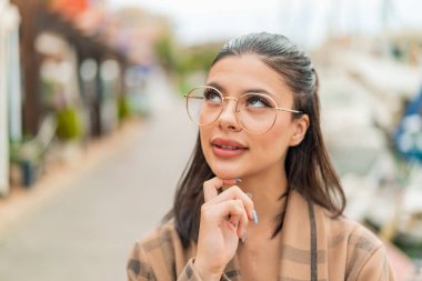 Genç ve güzel bir kadın gözlüklü ve yukarı bakıyor.