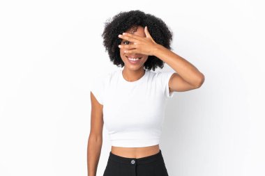 Beyaz arka planda izole edilmiş genç Afrikalı Amerikalı bir kadın. Gözleri elleriyle kaplıyor ve gülümsüyor.
