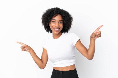 Beyaz arka planda izole edilmiş genç Afrikalı Amerikalı kadın parmak uçlarını işaret ediyor ve mutlu.