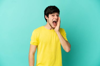 Genç Rus adam mavi arka planda mahsur kalmış, şaşırmış ve şok olmuş bir yüz ifadesi var.