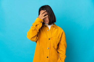 Mavi arka planda başağrısı olan genç Latin bir kadın.