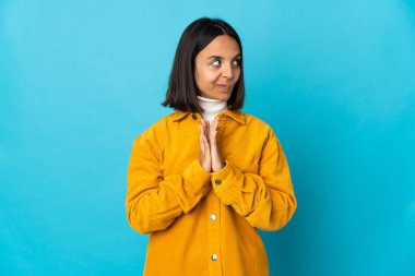 Mavi arka planda izole edilmiş genç Latin kadın bir şeyler planlıyor.