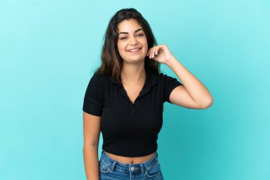 Mavi arka planda izole edilmiş genç beyaz kadın gülüyor.