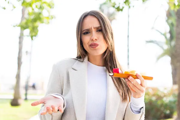 Young Pretty Woman Holding Sashimi Outdoors Making Doubts Gesture While — Stock Photo, Image