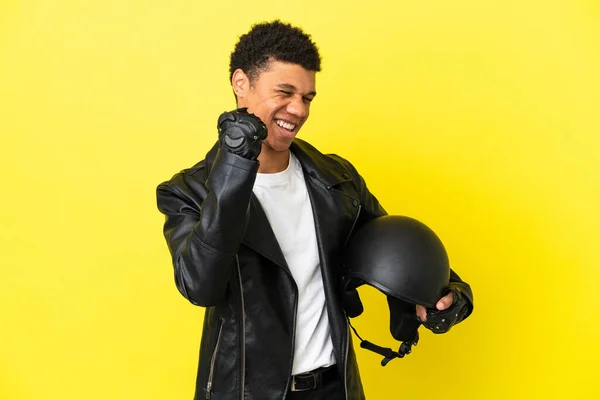 年轻的非洲裔美国人头戴摩托车头盔 被黄色背景隔离 庆祝胜利 — 图库照片