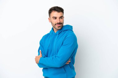 Beyaz arka planda izole edilmiş genç beyaz adam yana bakıyor ve gülümsüyor.