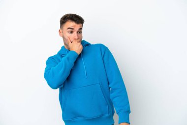 Beyaz arka planda izole edilmiş genç beyaz adam yan tarafa bakarken sürpriz jest yapıyor.