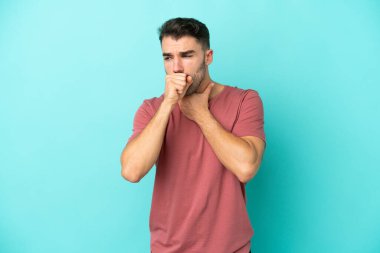 Kafkasyalı genç adam mavi arka planda izole edilmiş, çok öksürüyor.