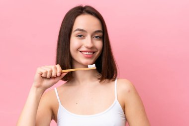 Genç Ukraynalı bir kadın pembe arka planda izole edilmiş diş fırçası ve mutlu bir ifadeyle
