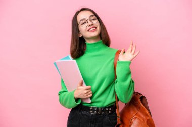 Genç öğrenci Ukraynalı kadın pembe arka planda izole edilmiş, mutlu bir ifadeyle selamlanıyor.