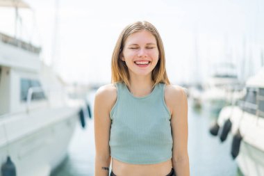 Açık havada genç sarışın bir kadın Neşeli bir ifadeyle