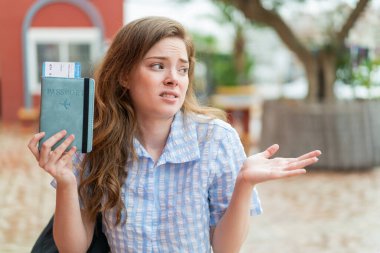 Kızıl saçlı genç bir kadın elinde pasaport tutarken yüzünde sürpriz bir ifade vardı.